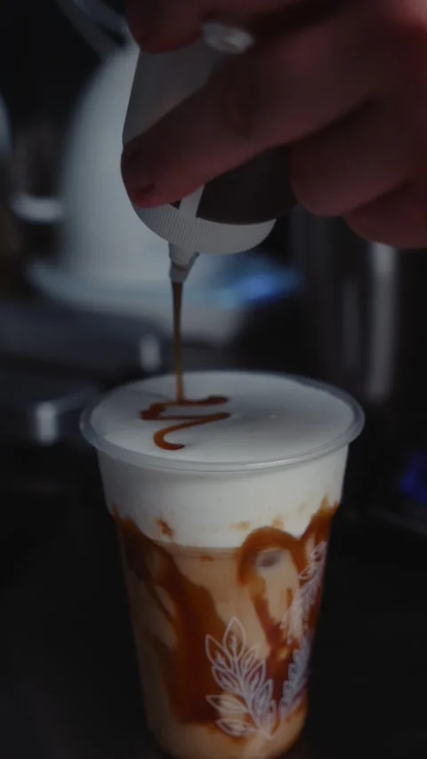 Drawing Decorative Pattern with Caramel Syrup on Milk Foam Stock Footage 339598840