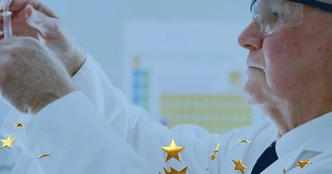Drawing fluid, senior tech in lab coat and goggles handling syringe in clinical Stock Photos
