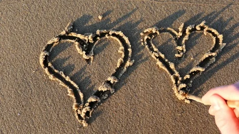 Drawing Heart Shape on Sandy Beach at Sunset Stock Footage 109356274