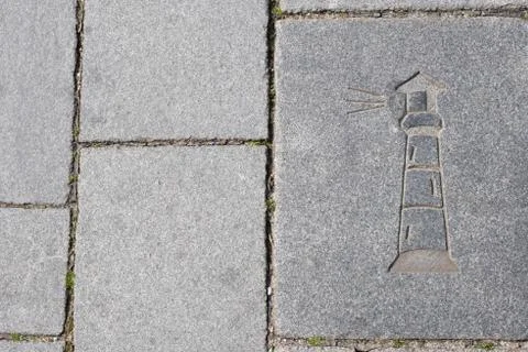Drawing of a lighthouse on a stone sidewalk in the old European port city Stock Photos