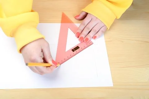 Drawing lines with a pencil and triangular ruler. 스톡 사진
