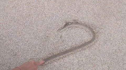 Drawing a love shape on the beach sand stock footage Stock Footage 247456174