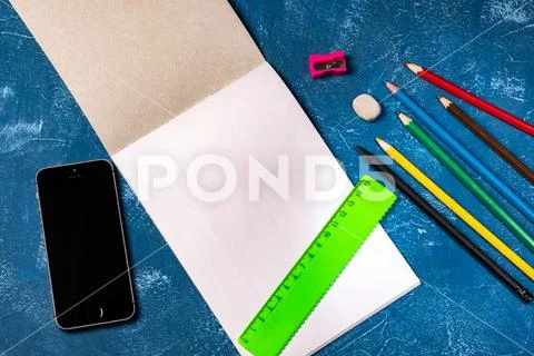 Drawing pad and colored pencils on blue background Stock Photos