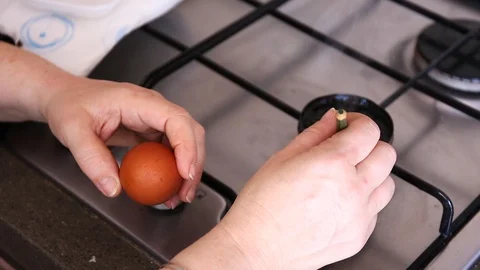 Drawing patterns with black wax with pencil on an egg near stove by woman hands Stock Footage 128637508