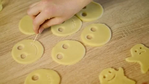 Drawing a smiling mouth on a raw cookie dough cutout with toothpick Stock Footage 342704165