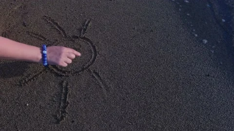 Drawing a smiling sun on sand while the waves are hitting the shore. 4K Stock Footage 195645043