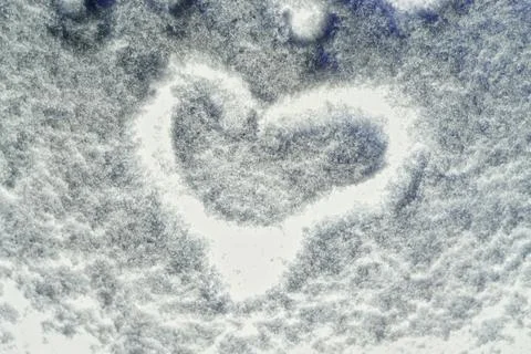 Drawing on the snow in the shape of a heart on a surface glowing from the ins Stock-Fotos