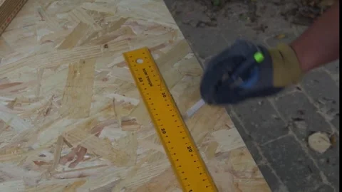 Drawing a straight line on a oriented strand board Stock Footage 313242406