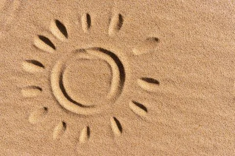 The drawing of the sun with sunbeams is hand-drawn on a golden sandy beach Stock Photos