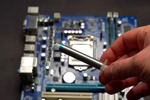 Drawing thermal paste on computer processor. Installing a cooling system on.. Stock Photos