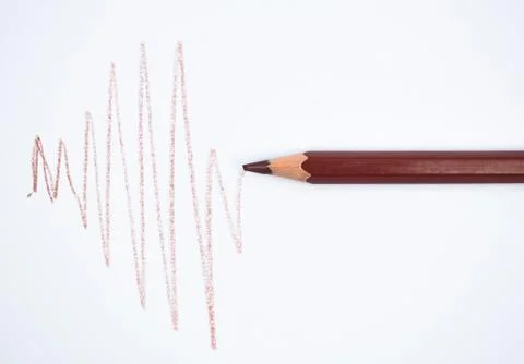 Drawing a zigzag line with a brown colored wood pencil crayons on a white pap Stock Photos