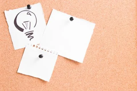 Drawn light bulb on a white sheet attached to a cork board with a pin, severa Stock Photos