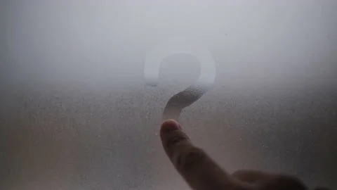 Draws a question mark on the window with your finger. The window was fogged up Stock Footage 146656488