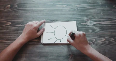Draws the sun with a marker on paper. Close-up top view teenager drawing Stock Footage 260939042