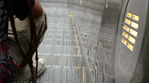 Dreadlock person sitting on moving escalator 스톡 동영상 25731485