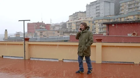 A dreadlocks man at the phone under the snow in a terrace Stock-Footage 86515688