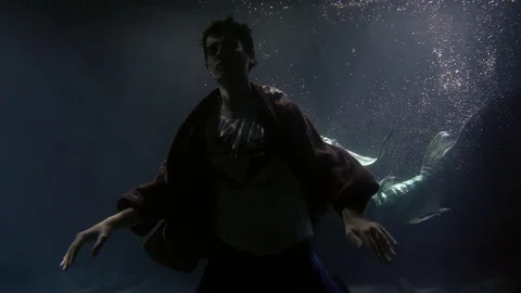 Dream of a man in Bathrobe around under the water a mermaid swimming with a fin Video stock 104706325