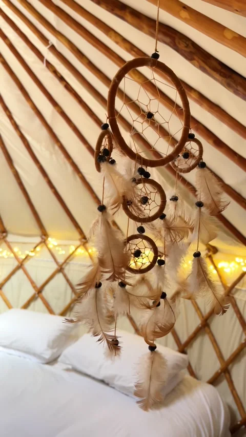 Dreamcatcher and cozy bed inside a luxury glamping yurt with warm fairy lights Stock Footage 344412762