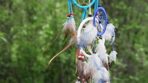A dreamcatcher with multi-colored feathers flutters in the wind against the Stock Footage 151203297