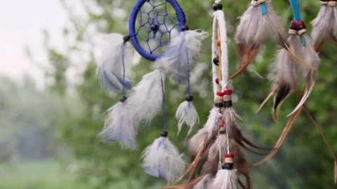 A dreamcatcher with multi-colored feathers flutters in the wind against the Stock Footage 151203428