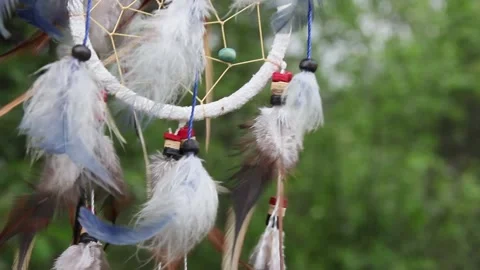 A dreamcatcher with multi-colored feathers flutters in the wind against the Stock Footage 151203529