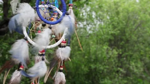 A dreamcatcher with multi-colored feathers flutters in the wind against the Stock Footage 151595280