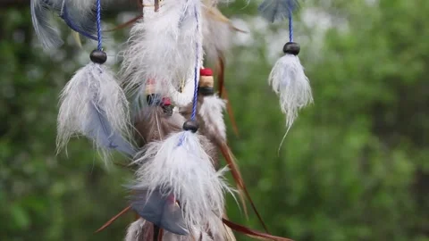 A dreamcatcher with multi-colored feathers flutters in the wind against the Stock Footage 151752536