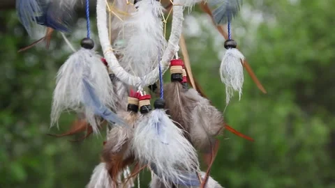 A dreamcatcher with multi-colored feathers flutters in the wind against the Stock Footage 152044024