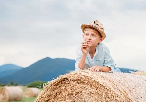 Dreaming boy lying on the rolling haystack Stock Photos