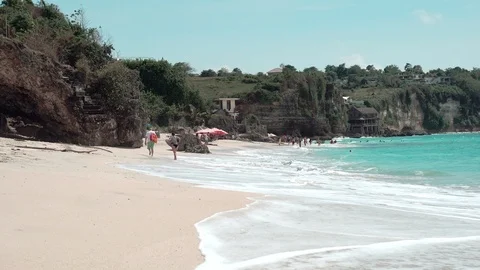 Dreamland sandy beach with foamy waves and tourists walking Stock Footage 87049507