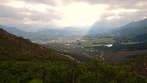 Dreamy god rays illuminate patchwork farm landscape of Franschhoek wine valley 動画素材 317174130