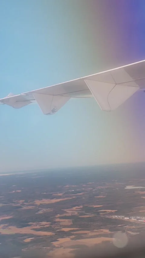 Dreamy passenger window view beneath an airplane wing over sunlit countryside Vídeos de archivo 336225086