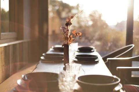 Dreamy view of sunlit dining table at cafe with bowls and flowers Stock Photos