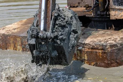 Dredging the bottom of water area, view of the bucket of the floating excavator Stock Photos