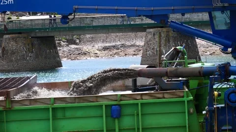 Dredging equipment extracts mud from riverbed into green container Stock Footage 340607212