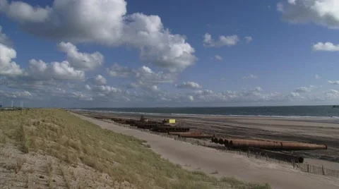 Dredging pipes lie against artificial dune with planted marram grass Stock Footage 44353176