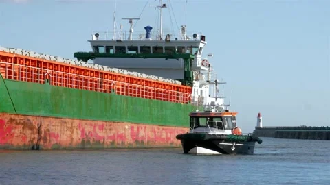 Dredging vessel entering harbor flanked by small ship pilot boat Stock-Footage 220038662