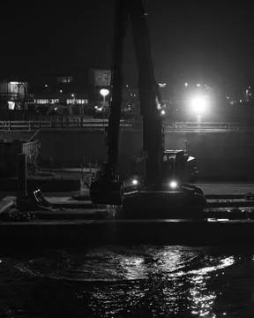 Dredging on the water at a large construction site in the evening Stock Photos