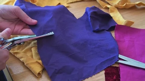Dress maker cutting purple fabric sample with scissors before sewing Stock Footage