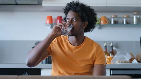 Dressed casually, a young African man takes a refreshing sip of water Stock Footage 279671811