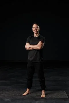 Dressed in dark elegance, the captivating man stands regally with hands Stock Photos