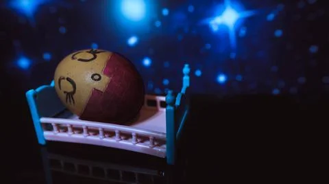 Dressed egg sleeps in bed, in the background of the star. Painted egg. Select Stock Photos