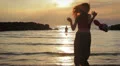 dressed woman in love runs to her man into the sea - hugs and kisses - sunset HD Footage