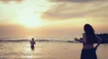 dressed woman in love runs to her man into the sea - hugs and kisses - sunset HD Footage