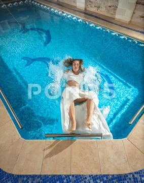Dressed woman slipped on floor at swimming pool and fell in water Stock Photos