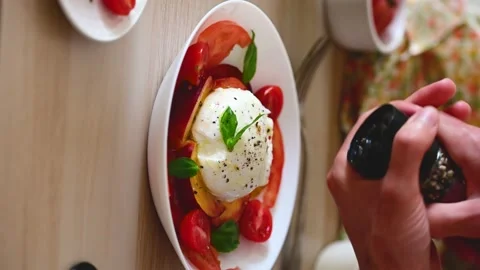 Dressing with freshly ground pepper on a burrata salad Stock Footage 219963661