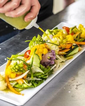 Dressing a Salad - the final step before chefs salad leaves the kitche Stock Photos