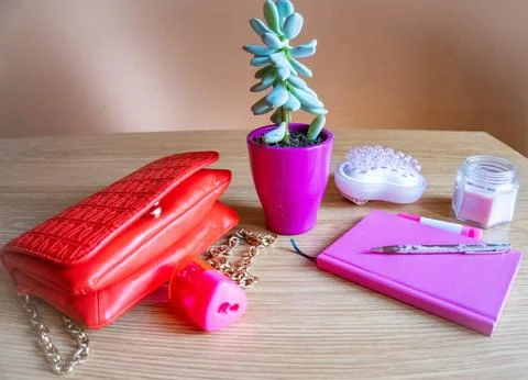 On the dressing table bag, flower, notebook, pen, candle all in pink tone Stock Photos