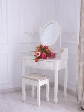 Dressing table with a mirror and flowers in the room. Stock Photos