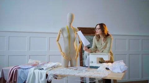 Dressmaker examines the text on the paper next to the mannequin near the mirror Stock Footage 127015771